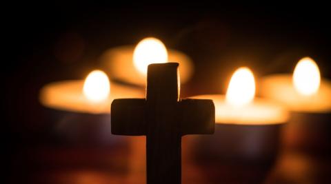 A cross in front of some candles, representing ecumenism.